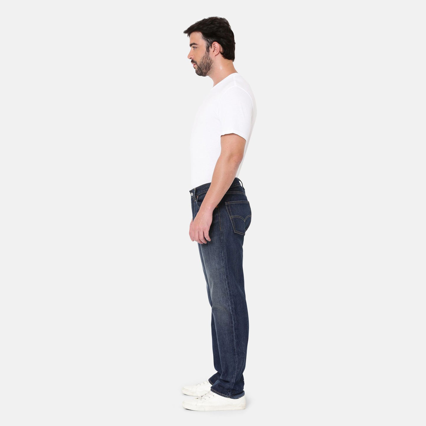 A man in a white t-shirt and Levis 555 Relaxed Straight denim blue jeans stands in profile against a plain background, paired with white sneakers.