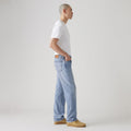 A person in a white t-shirt and Levis 555 Relaxed Straight, vintage-inspired jeans stands sideways against a plain background.