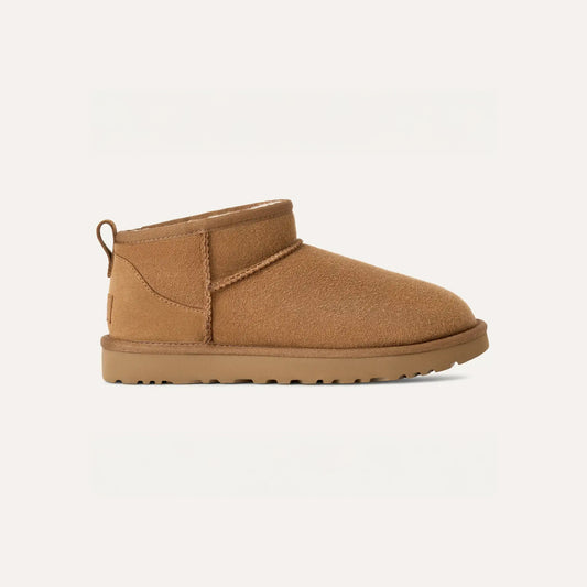 An Ugg W Classic Ultra Mini boot in tan, with an ultra-lightweight sole and rounded toe, is displayed against a plain background.