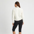 Dressed in Rohnisch's Thermal Half Zip Fleece, a person stands with their back turned against a simple white backdrop, showcasing effortless style paired with black leggings.