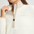 A person adjusts the zipper of a white Thermal Half Zip Fleece by Rohnisch, highlighting its sleek, cropped design.