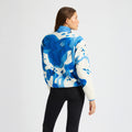 A person models the Rohnisch Thermal Half Zip Fleece, featuring a blue and white abstract pattern with a cropped style, paired with black leggings against a plain backdrop.