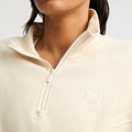 A person wearing the "Soft Sweat Half Zip" by Rohnisch, crafted from beige terry fabric, featuring an embroidered logo on the chest.