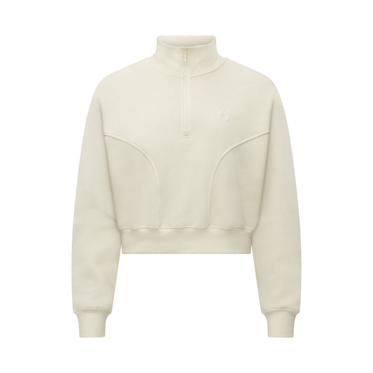 The Rohnisch Soft Sweat Half Zip, a cream-colored cropped sweatshirt, features a minimalist design with a high collar. Crafted from premium terry quality fabric, it offers a snug fit that effortlessly blends style and comfort.