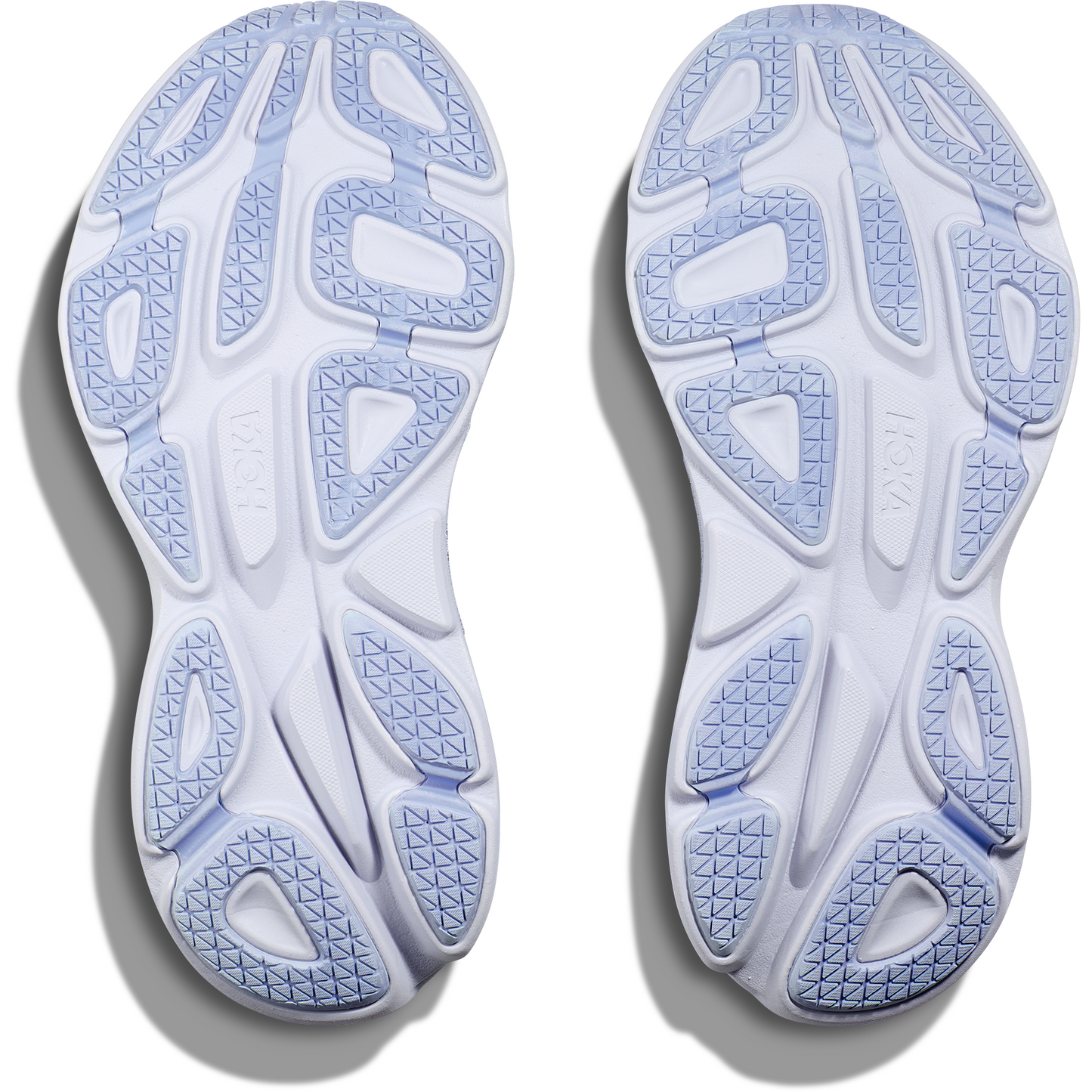 A pair of white sneakers with textured blue soles viewed from the bottom, showcasing the tread pattern and design. The Hoka W Bondi 8, Ether/Illusion features extended heel geometry and softer foams for enhanced comfort and support.