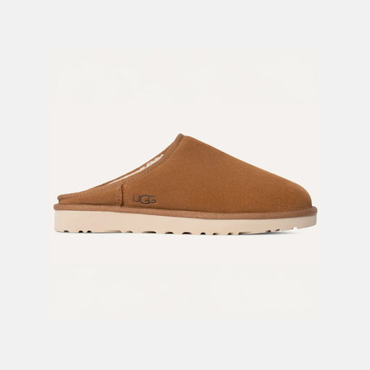 M Classic Slip-On, a brown shoe by Ugg, combines sheepskin and suede with a flat sole. The "UGG" label is on the side, featuring UGGplush™ for comfort, shown on a plain white background.