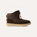 The UGG "All Gender Campfire Crafted Regenerate" is a dark brown ankle boot with decorative stitching, a tan sole, and leather lace detail on the side. It features a cozy UGGplush™ liner for added comfort against a plain background.