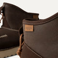 Close-up of All Gender Campfire Crafted Regenerate UGG boots in brown suede, labeled "regenerate by UGG." They feature white stitching, brown laces, and a cozy UGGplush™ liner. Inspired by regenerative agriculture, these sheepskin boots blend sustainability with style for a comfortable fit.