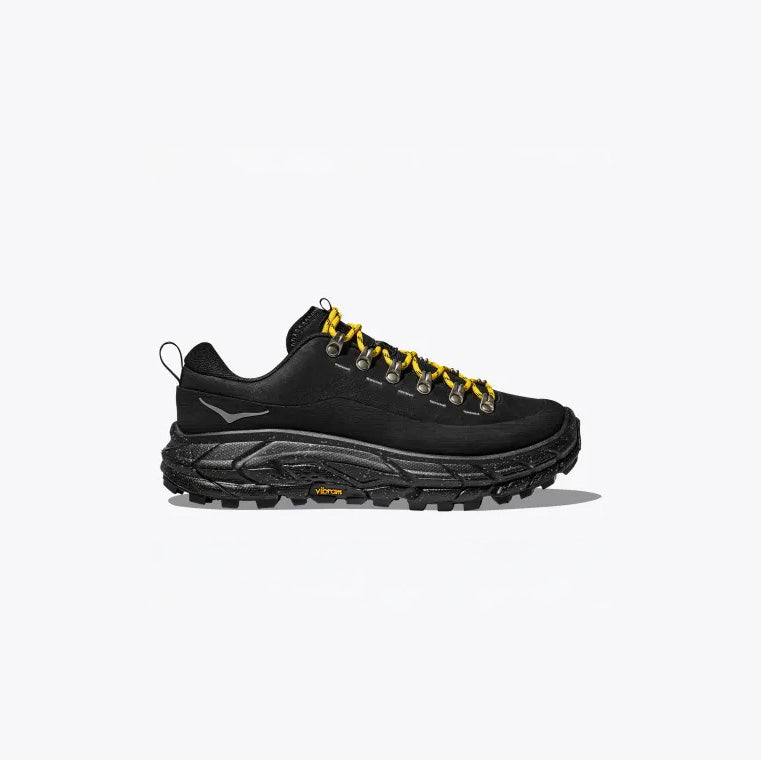 The U Tor Summit Black by Hoka features HOKA cushioning, a chunky sole, yellow laces through metal eyelets, and a heel loop, set against a plain background.