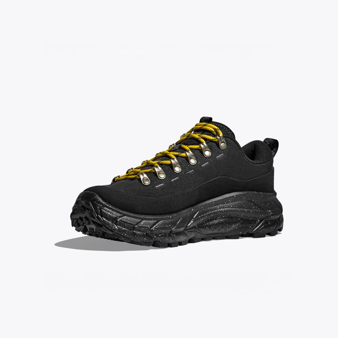 The Hoka U Tor Summit in black is a hiking shoe made of nubuck leather, featuring a chunky textured sole, metallic eyelet hardware, and vibrant yellow laces on a plain white background.