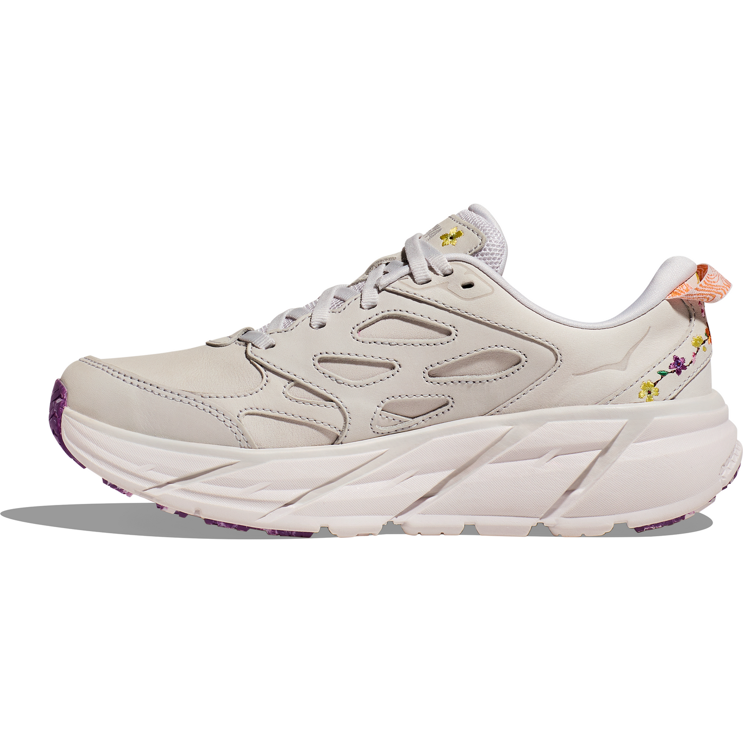 A white athletic shoe with a thick, chunky sole, floral embroidery on the back, and purple tread on the bottom offers a lightweight ride reminiscent of the Hoka W Clifton L BP, Nimbus Cloud/Nimbus Cloud.