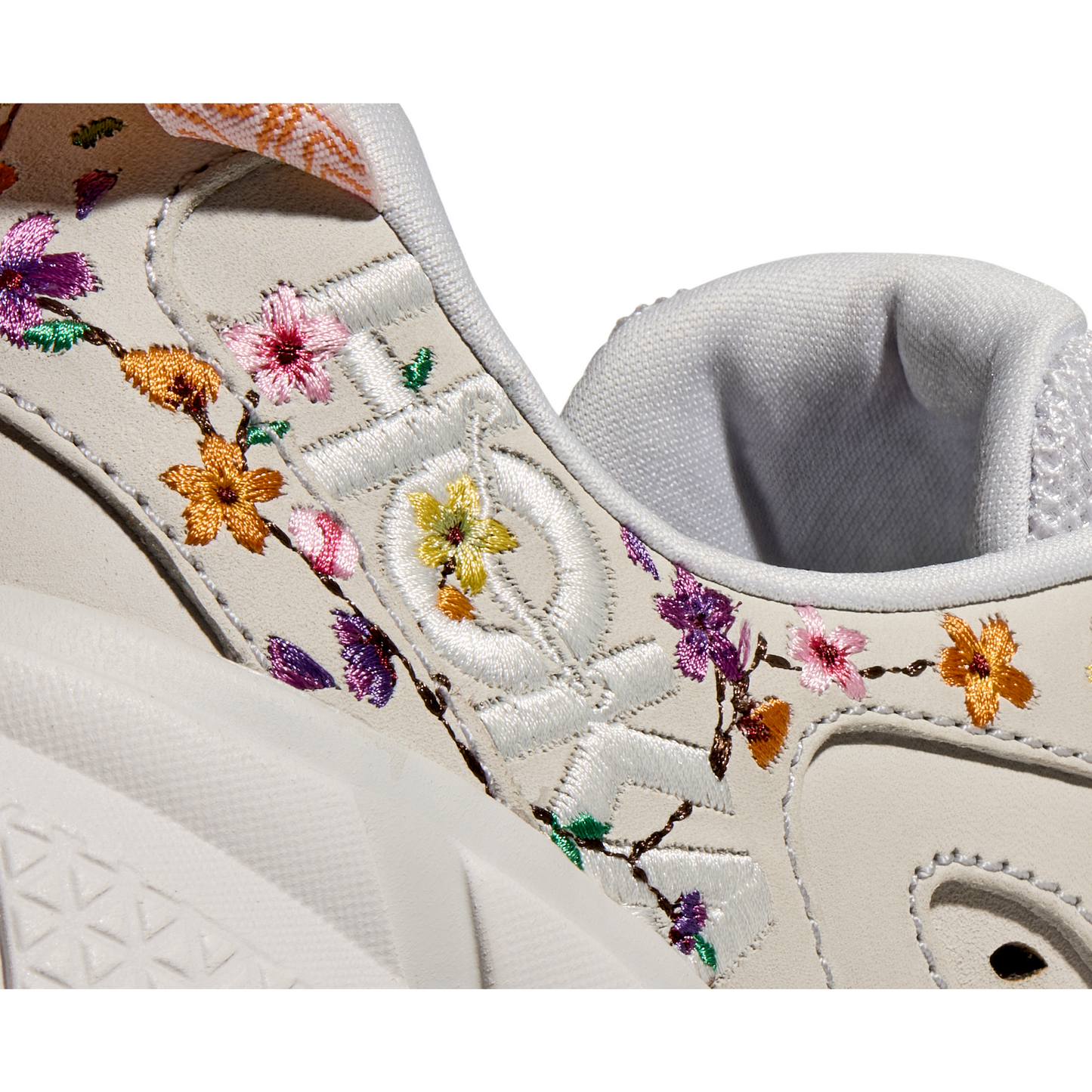 Close-up of a white Hoka W Clifton L BP, Nimbus Cloud/Nimbus Cloud sneaker with intricate multicolored floral embroidery on the side, featuring pink, purple, and yellow flowers with green stems. This design not only offers visual appeal but also ensures a lightweight ride for comfort and style.