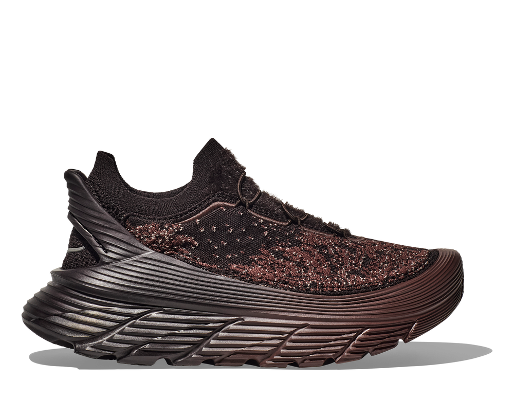 A side view of the Hoka U Restore Chukka Paria Farzaneh, a black unisex sneaker featuring a sleek design with intricate weaving and a thick, textured sole.