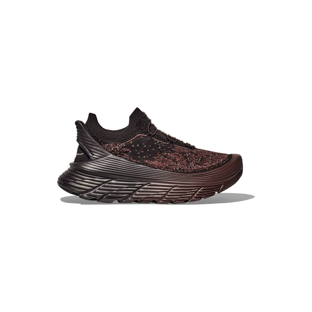 The Hoka U Restore Chukka by Paria Farzaneh, a unisex athletic shoe in black and red with a thick, textured sole, is showcased on a light gray background.