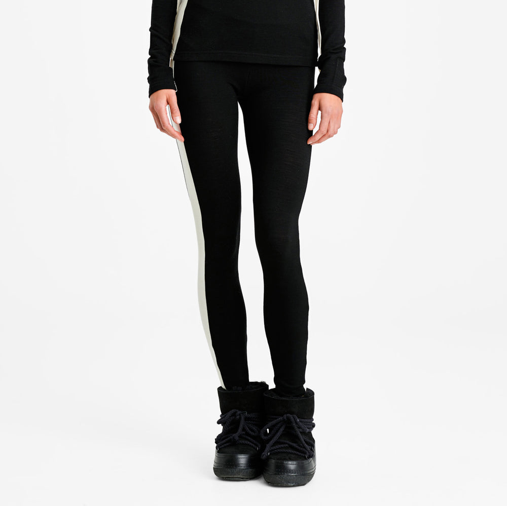 A person in We Norwegians' W Voss Leggings, featuring black fabric with white side stripes and styled for women, pairs them with black boots against a white background.