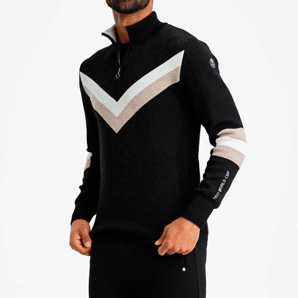 A person wears the M Hafjell Zip Up by We Norwegians, a black Merino wool sweater with white and beige chevron patterns and matching sleeve stripes. Crafted in China for men, it offers a stylish and tailored fit.