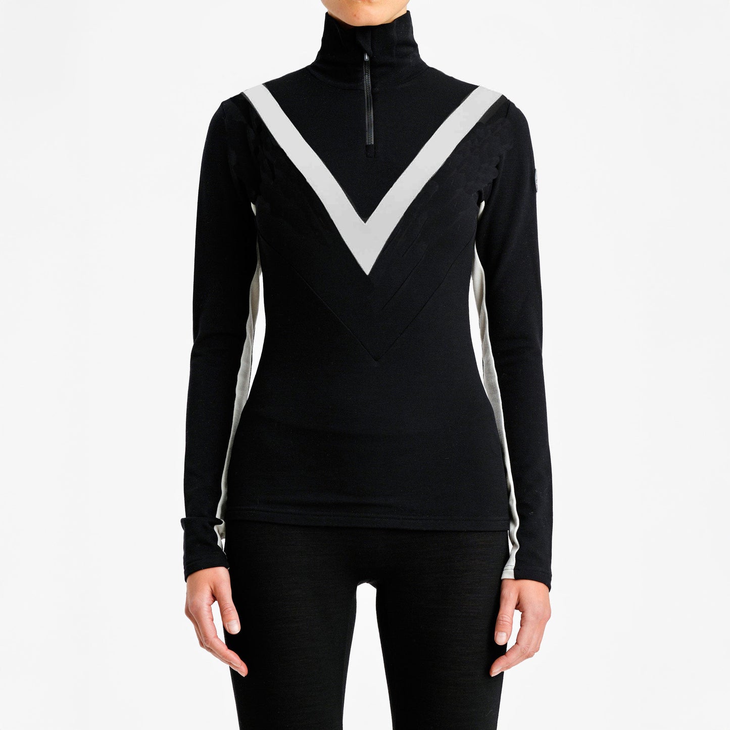 A model in a W Voss Chevron Zip-Up by We Norwegians, featuring a black turtleneck with white chevron pattern from soft Merino wool, paired with sleek black pants. Styled in women's sizing against a pristine white background.