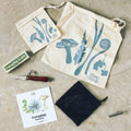 A FarmSteady Foraging Tool Kit includes two drawstring bags, a pocket knife, a mesh bag, a tool replacement part, and a booklet titled "Foraging Toolkit.