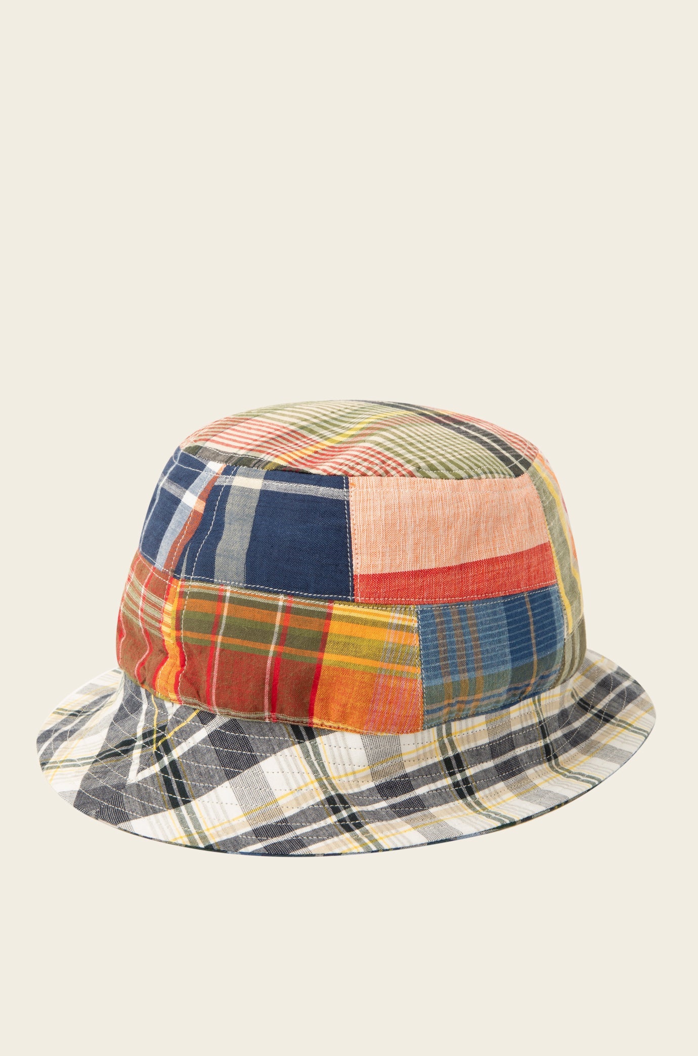 The "Reversible Bucket Hat, Blue Multi" from Original Madras Trading Co. showcases a patchwork design with an array of vibrant plaid and striped fabric patterns.