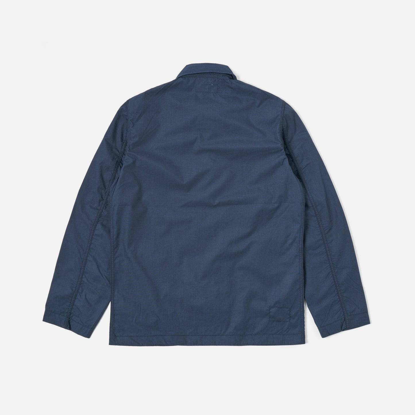 The image displays the Universal Works Recycled Poly Tech Bakers Jacket in navy, shown from the back on a plain white background. It features long sleeves and a collared neckline.