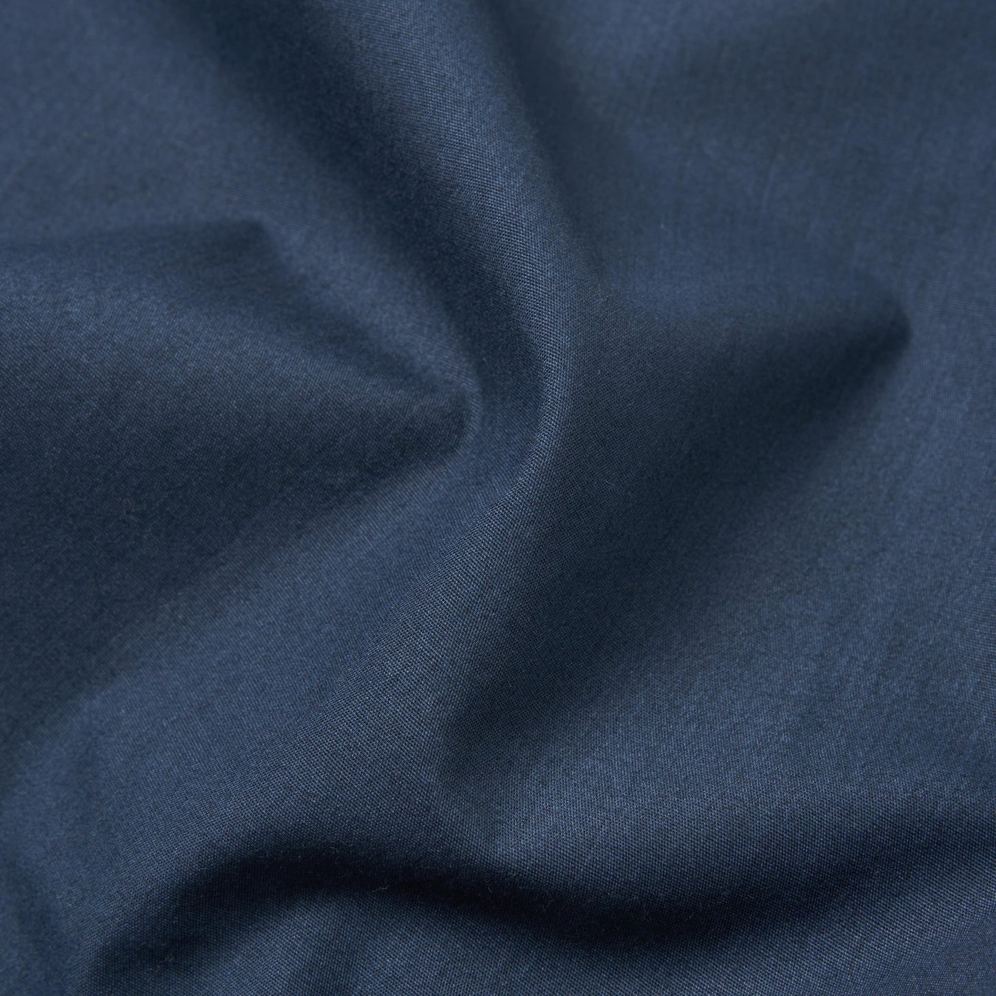 A detailed view of the Recycled Poly Tech Bakers Jacket in Navy by Universal Works, showcasing its soft folds and creases.