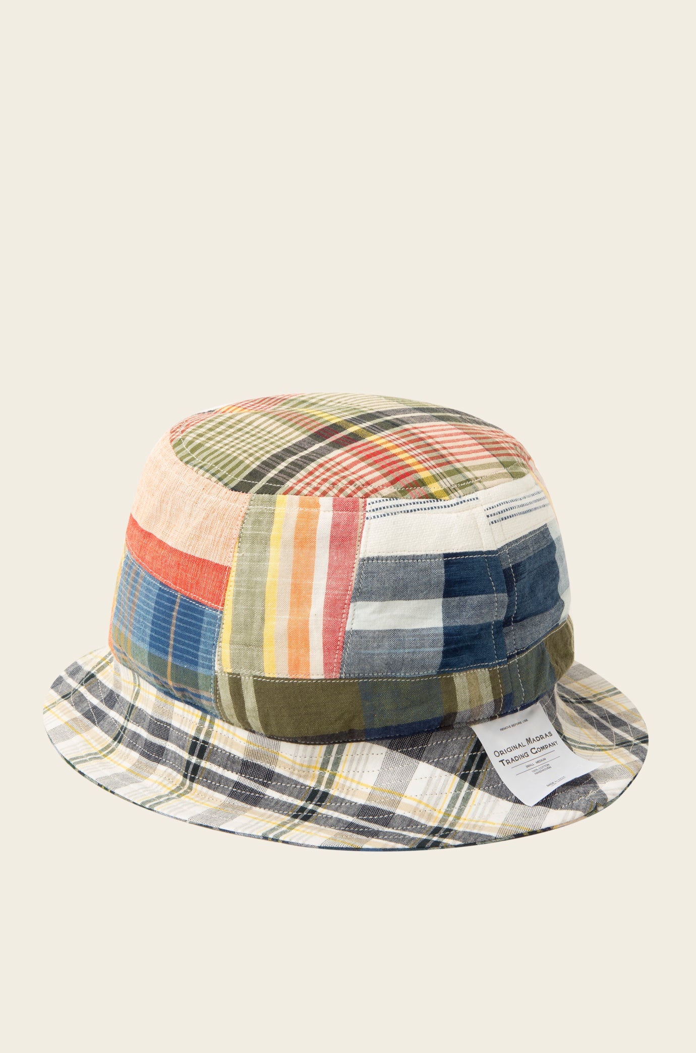 A reversible bucket hat by Original Madras Trading Co. in blue multi, crafted from various multicolored patchwork fabric and featuring a small white label on the brim.