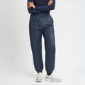 A person in Rohnisch Relaxed Quilt Pants made from recycled navy ripstop polyester and silver sneakers stands against a white backdrop.