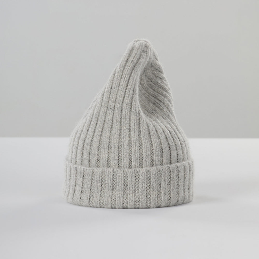 The Le Bonnet Large Beanie in Silver, made in Scotland, is a chunky ribbed knit with a pointed top, displayed upright against a light surface and plain background.