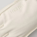 A close-up of a Hestra leather ski glove from the Wakayama line in Almond/White shows "Hestra" embossed on the supple cowhide back.