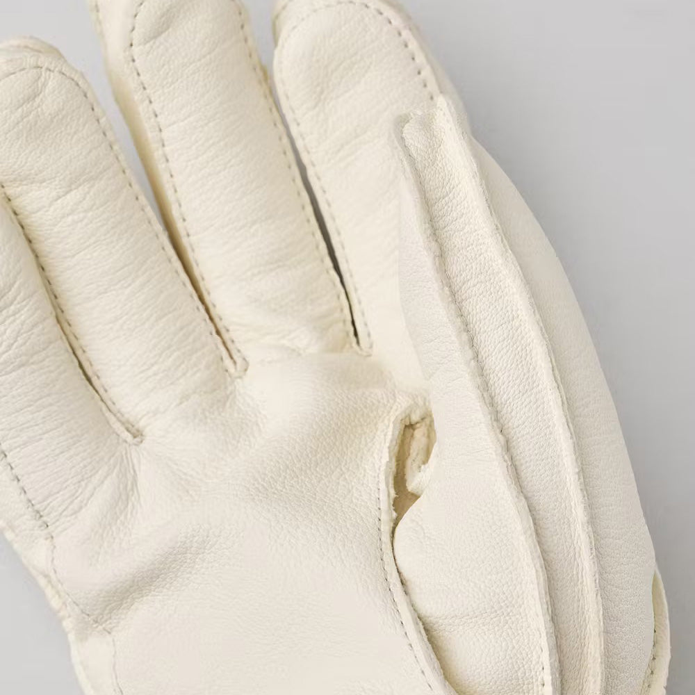 A close-up of the Hestra Wakayama glove in almond/white shows off its intricate stitching against a pale background.