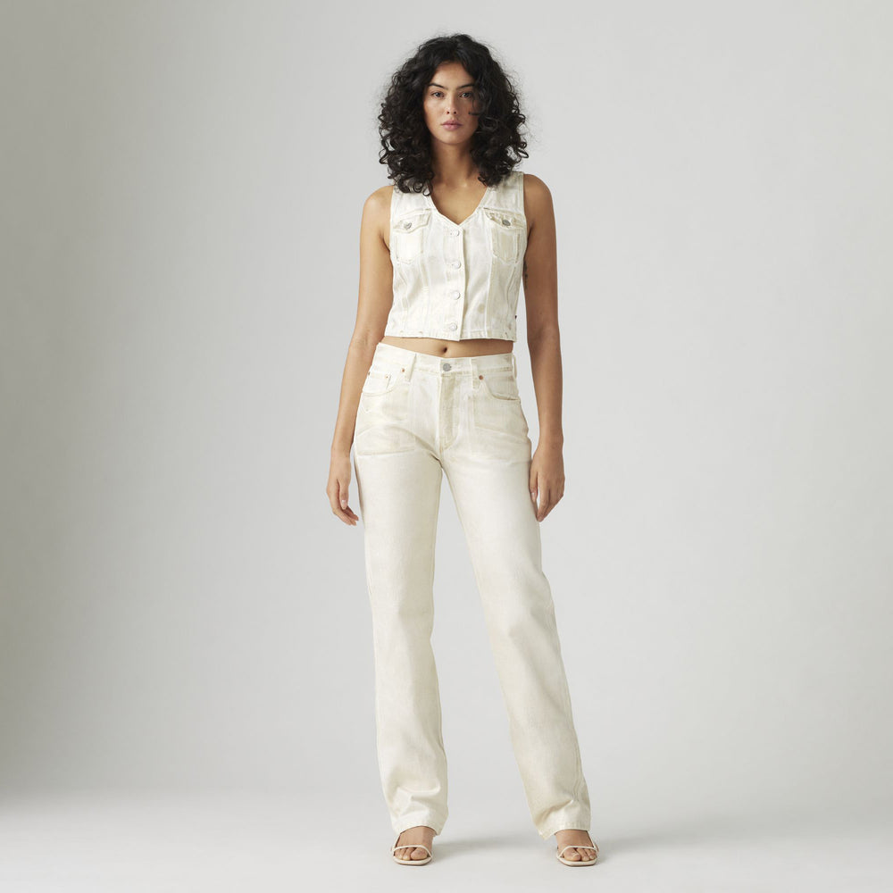 A person models the Levis 501 90s collection, featuring a sleeveless white denim jacket paired with matching mid-rise jeans, against a plain backdrop.