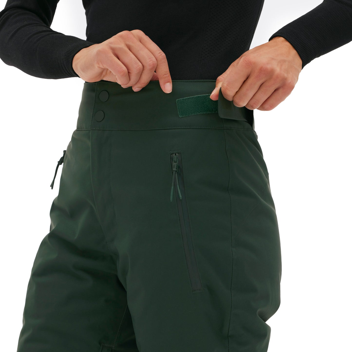 Someone is adjusting the waistband of Alessandra Pant by Halfdays, a classic green design featuring zippered pockets.