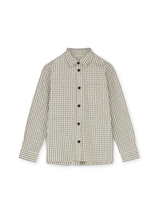 The Ashly Shirt Check by Aiayu is a long-sleeved, button-up versatile work shirt with a beige and white checkered pattern. It features a collar and handmade horn buttons, and is crafted from 100% regenerative cotton for ultimate comfort and sustainability.