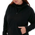 A person wears a black Bonnie Fleece Top from Halfdays, a performance mid-layer designed for high-alpine classics, with one hand casually resting in the pocket, partially visible from the shoulders down.