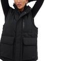 A person is wearing the Halfdays Davis Convertible Jacket, a sleeveless black quilted vest with large pockets, a high collar, and raised arms. The jacket displays its versatility by transforming into a stylish piece with removable sleeves.