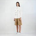 A person wears a Herno W Light Linen DB Blazer in Bianco, beige knee-length shorts, and white sneakers, standing against a plain background.