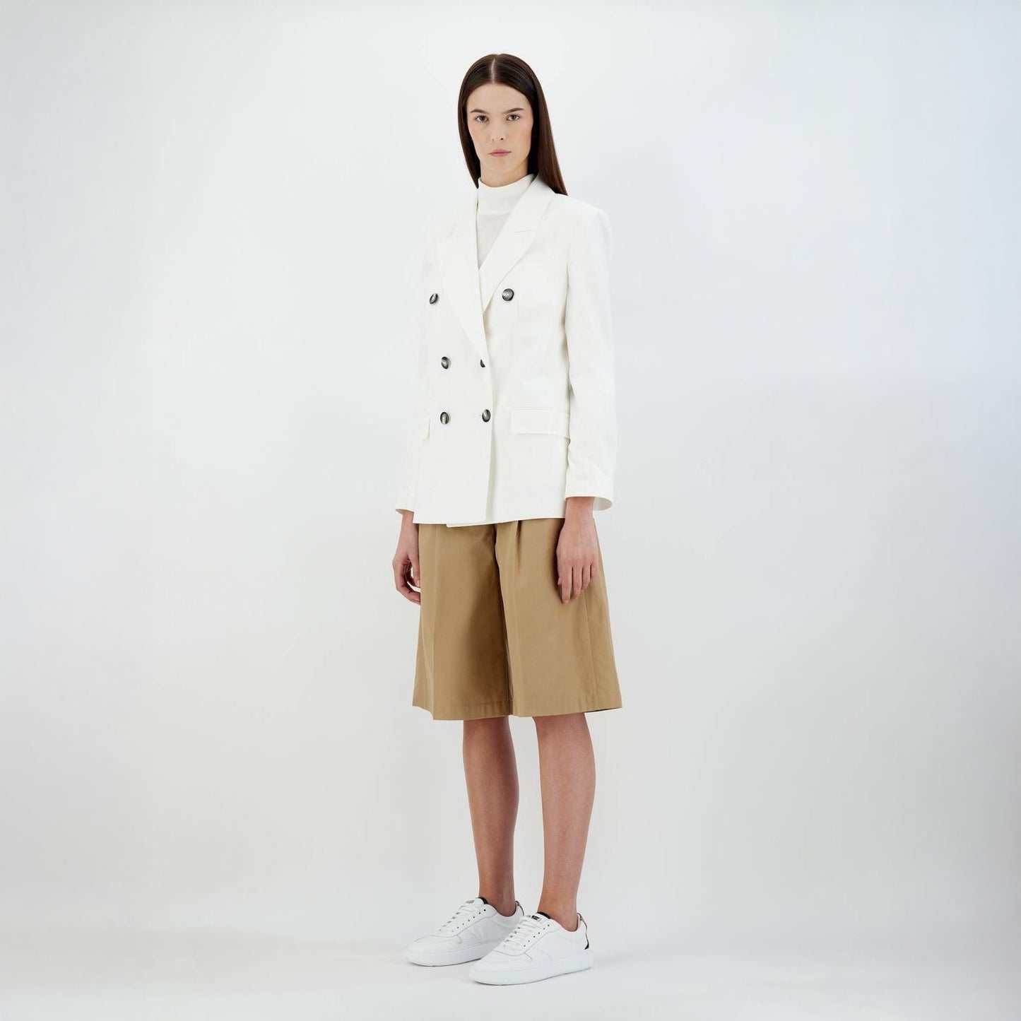 A person wears a Herno W Light Linen DB Blazer in Bianco, beige knee-length shorts, and white sneakers, standing against a plain background.