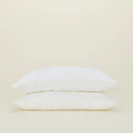 Two white pillows stack elegantly against a plain beige background, dressed in Hawkins New York's Standard Linen Pillow Case.