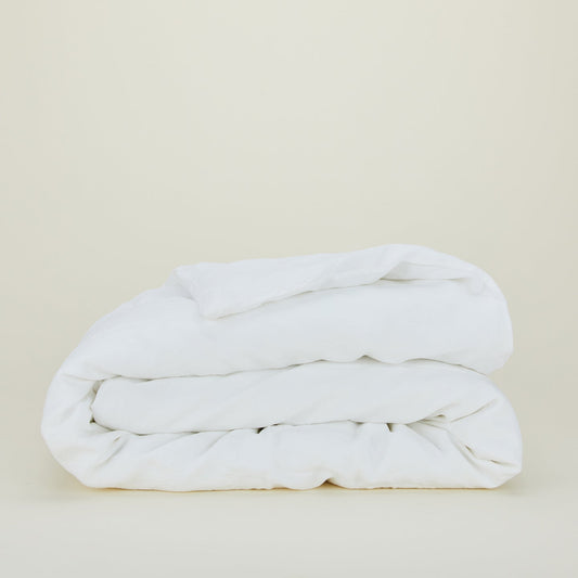 A neatly folded Simple Linen Bedding - King Duvet Cover by Hawkins New York is placed against a plain, light-colored background.