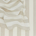 Close-up of beige and white striped fabric from Hawkins New York's Essential Striped Dinner Napkins (Set of 4), draped with soft folds, ideal for relaxed pieces or home basics.