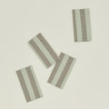 Four Essential Striped Dinner Napkins from Hawkins New York, featuring green and gray stripes, are arranged on a light background.