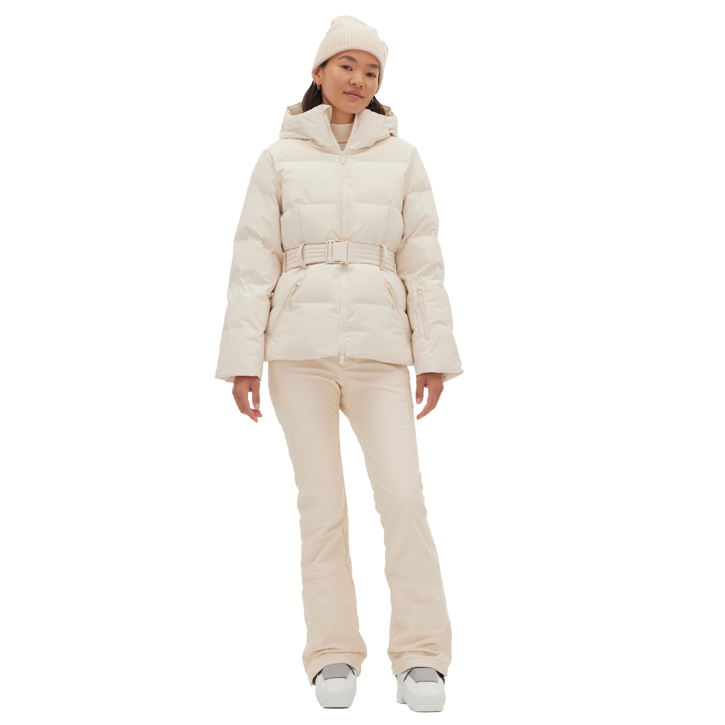 A person wearing a cream-colored Hedy Puffer Jacket by Halfdays, along with matching pants, a beanie, and boots, stands on a white background.