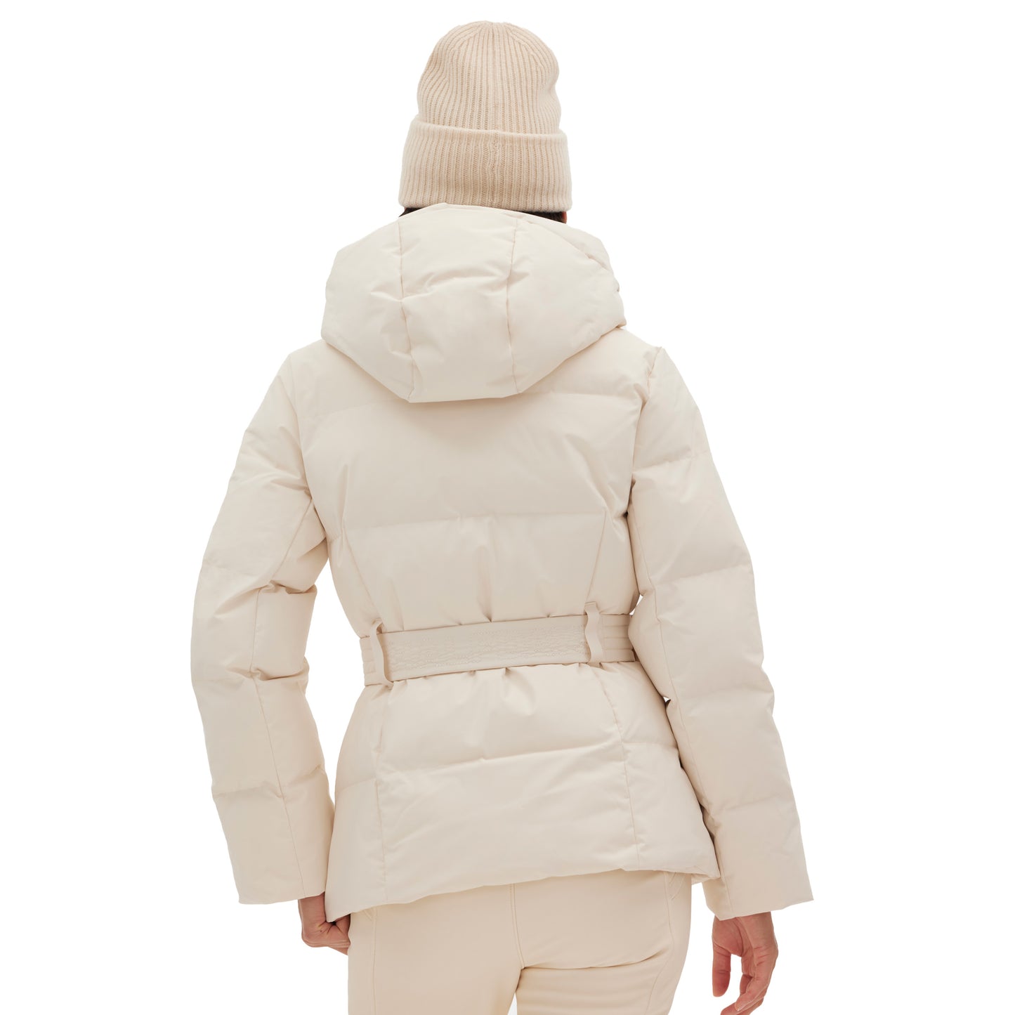 Seen from the back, a person is wearing the Halfdays Hedy Puffer Jacket in beige with a hood, complemented by a matching knit hat—perfect for the slopes.