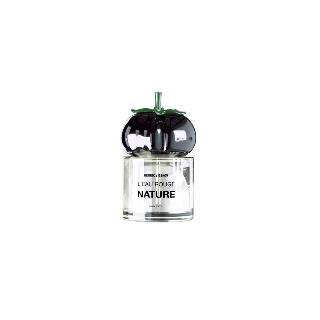 Perfume bottle with a black, apple-shaped cap and "L'eau Rouge Nature" text on the label from Henrik Vibskov exudes a cruelty-free allure.