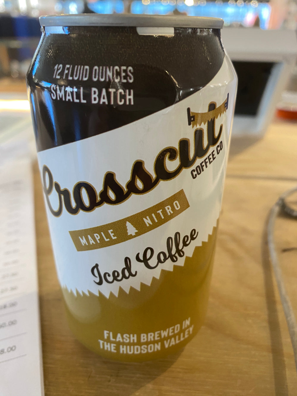 A 12 fl oz can of Westerlind's Crosscut Maple Nitro Iced Coffee sits on a table, labeled as small batch and flash brewed in the Hudson Valley.