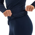 Adjusting the waistband of dark leggings, this person is clad in a Johnson top by Halfdays, exemplifying an active outdoor fit that offers both style and comfort.