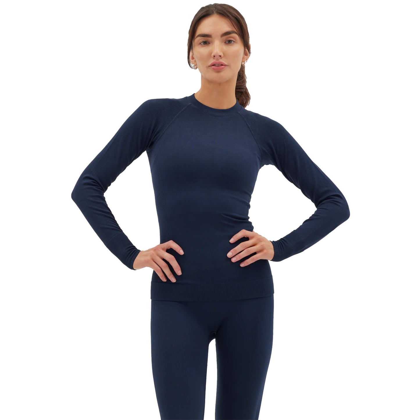 A person wearing a navy Johnson top from Halfdays and leggings, showcasing an active outdoor fit, stands confidently with hands on hips against a white background.