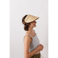 A person wearing a striped tank top and a sleek Lola Hats Marquee Visor, Natural w/ Brown Leather, standing against a plain white background.