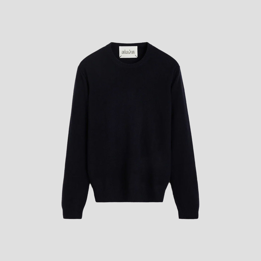 The Aiayu Leonardo Cashmere Sweater, a unisex black crew neck, stands out against a gray background and is ideal for any genderless wardrobe.