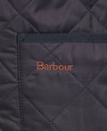 Close-up of the Barbour Quilted Zip-In Liner made from diamond quilted nylon fabric, featuring a patch pocket with "Barbour" embroidered in orange thread on the pocket.